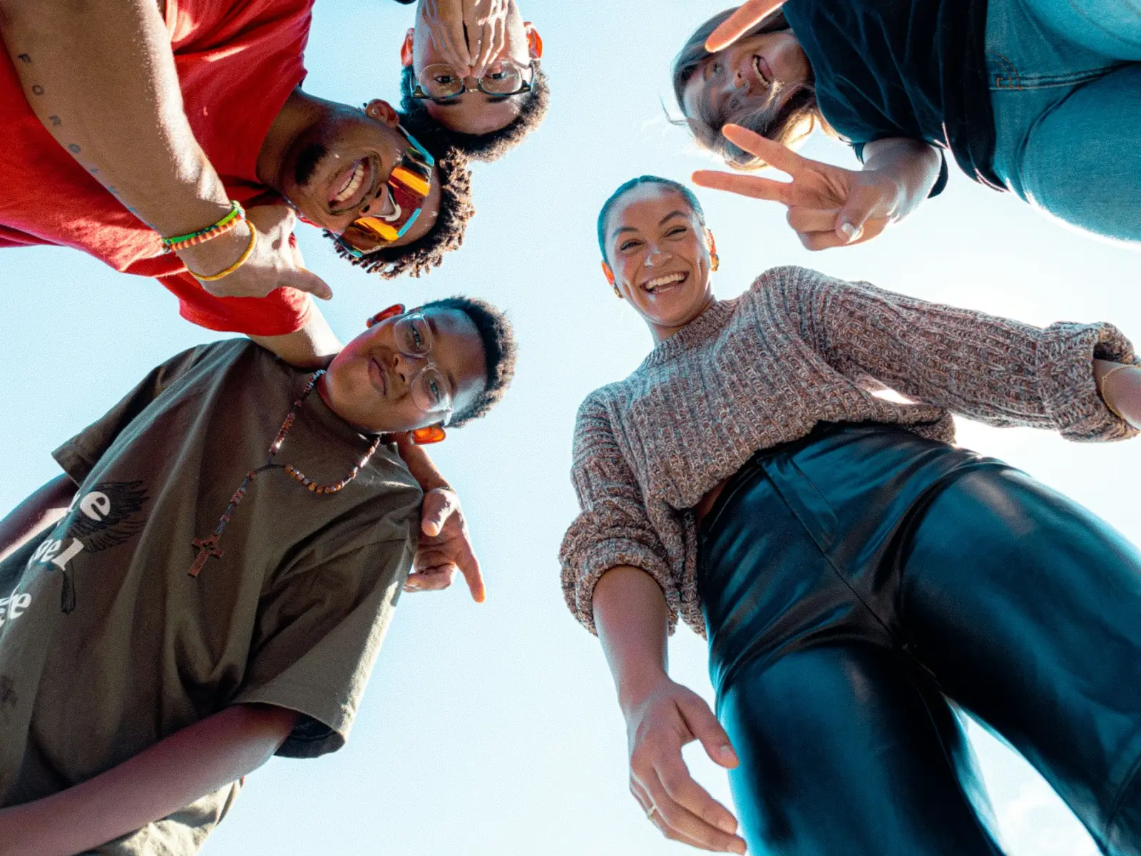 Six friends in a circle grinning down at the camera